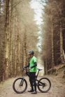 Mountainbiker fährt auf Feldweg zwischen Baum im Wald — Stockfoto