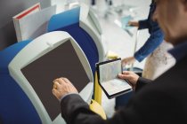Бизнесмен с помощью автомата самообслуживания при регистрации в аэропорту — стоковое фото