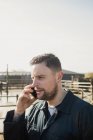 Young farmer talking on cellphone at farm against sky — Stock Photo
