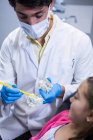 Dentist explaining mouth model to young patient at dental clinic — Stock Photo