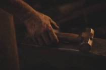 Hand of blacksmith holding hammer in workshop — Stock Photo