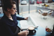 Бізнес-леді з кавовою чашкою читання газет в кафе — стокове фото