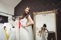 Femme souriante essayant robe de mariée dans le magasin — Photo de stock