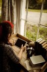Vista de ángulo alto de la mujer joven utilizando tableta digital por mesa en casa - foto de stock