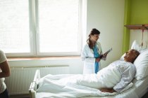 Жінка-лікар взаємодіє з літнім чоловіком в лікарні — стокове фото