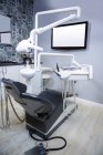 Cadeira de odontologia profissional e ferramentas de dentista na clínica — Fotografia de Stock