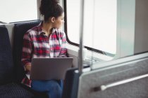 Woman looking through window while sitting in train — Stock Photo