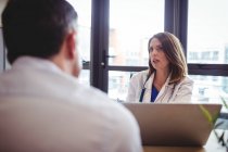 Жінка-лікар за столом розмовляє з пацієнтом у лікарні — стокове фото