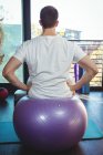 Back view of Male patient sitting on exercise ball in clinic — Stock Photo