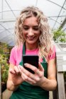 Fleuriste féminine utilisant téléphone portable dans le centre de jardin — Photo de stock