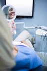 Patient checking her teeth in mirror at dentist clinic — Stock Photo