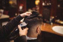 Hombre consiguiendo su pelo recortado con trimmer en peluquería - foto de stock
