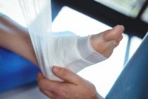 Image recadrée du thérapeute masculin mettant bandage sur le pied du patient féminin en clinique — Photo de stock