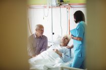 Старшая пара взаимодействует с медсестрой в больнице — стоковое фото