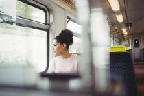 Ragionevole donna intelligente guardando attraverso la finestra mentre seduto in treno — Foto stock
