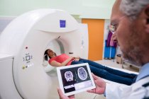 Врач смотрит на МРТ мозга на цифровом планшете в больнице — стоковое фото