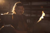 Кузнец держит в мастерской сварочную трубу — стоковое фото