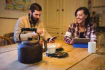 Mann und Frau nutzen digitales Tablet und Handy zu Hause — Stockfoto