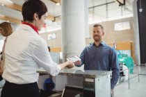 Airline check-in attendant handing passport to passenger at airport check-in counter — Stock Photo