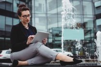 Повна довжина бізнес-леді, використовуючи цифровий планшет біля фонтану — стокове фото