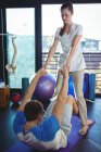 Female physiotherapist assisting male patient while exercising in clinic — Stock Photo