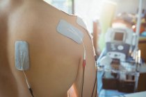 Back view of male patient with electro stimulation electrodes on his back in clinic — Stock Photo