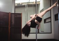 Vista posteriore della ballerina polacca che pratica la pole dance in palestra — Foto stock