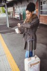Mulher verificando o tempo de pé na plataforma da estação ferroviária — Fotografia de Stock