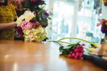 Cropped image of female florist holding flower bouquet at her flower shop — Stock Photo