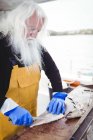 Close up of fisherman filleting fish in boat — Stock Photo