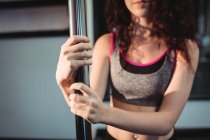 Abgeschnittenes Bild einer Pole-Tänzerin mit Stange im Fitnessstudio — Stockfoto