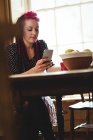 Mulher bonita usando telefone na mesa em casa — Fotografia de Stock