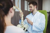Fisioterapeuta explicando coluna vertebral para paciente do sexo feminino na clínica — Fotografia de Stock