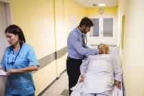 Médico examinando paciente sênior no corredor hospitalar — Fotografia de Stock