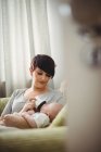 Mother feeding baby in living room at home — Stock Photo