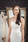 Портрет усміхненої жінки, яка намагається на весільній сукні в магазині — стокове фото