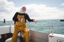 Рыбак держит чашку кофе на лодке — стоковое фото