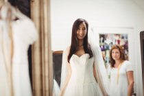 Mujer sonriente probándose el vestido de novia en la tienda - foto de stock