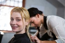 Cabeleireiro pentear o cabelo do cliente no salão — Fotografia de Stock