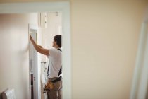Carpenter measuring door frame at home — Stock Photo