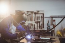 Male welder working on piece of metal in workshop — Stock Photo