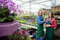 Retrato de dos floristas femeninas sonriendo en el centro del jardín - foto de stock