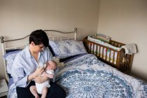 Mère nourrissant bébé avec biberon dans la chambre à coucher à la maison — Photo de stock