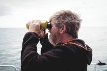Pescatore che guarda attraverso il binocolo dalla barca — Foto stock