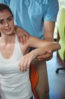 Porträt der Physiotherapeutin, die den Arm einer Patientin in der Klinik streckt — Stockfoto