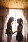 Young couple holding hands against window at home — Stock Photo