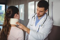 Физиотерапевт осматривает шею пациентки в клинике — стоковое фото