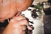 Close-up of goldsmith examining diamond through loupe in workshop — Stock Photo