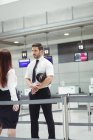 Piloto e comissária de bordo que interagem entre si no terminal do aeroporto — Fotografia de Stock