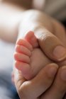 Cropped image of mother holding baby feet at home — Stock Photo